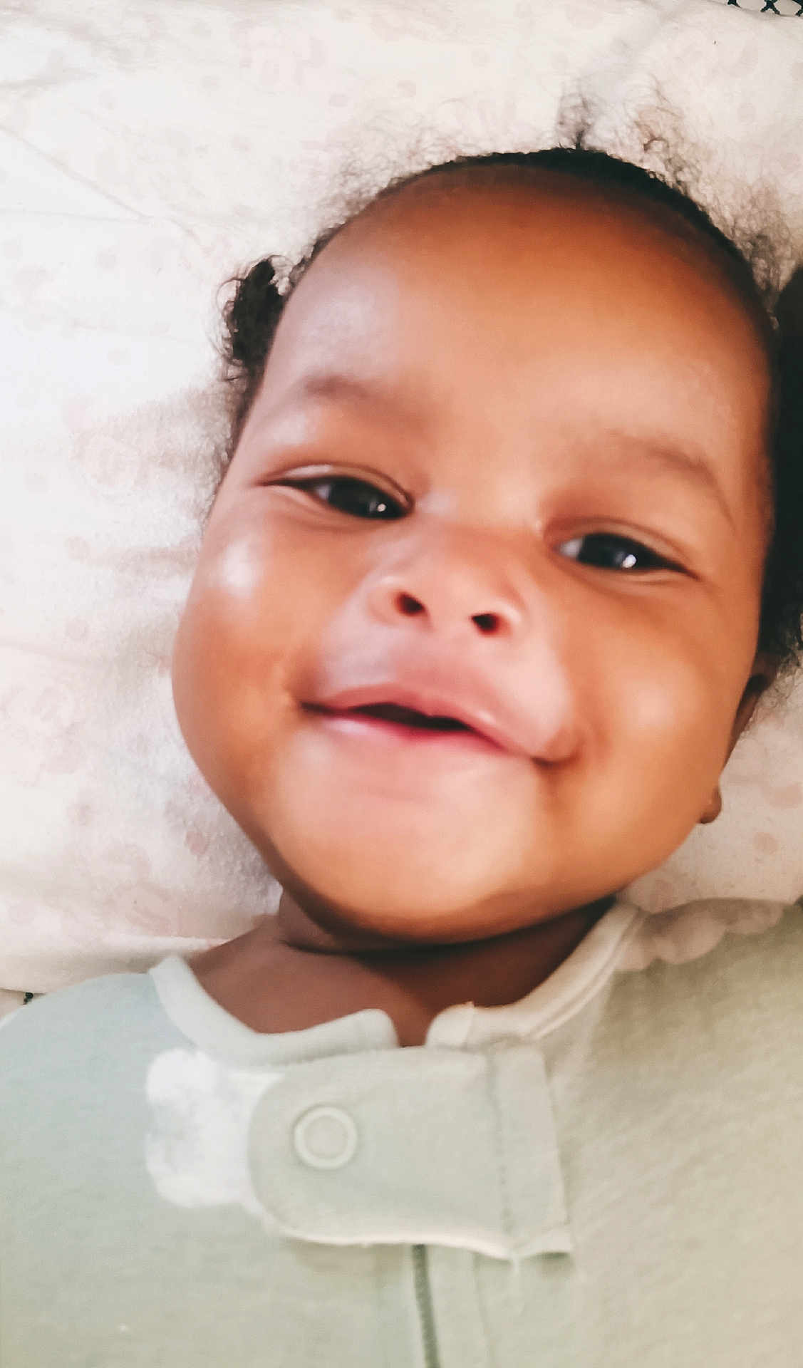 Chaanayah joined the competition — help win amazing prizes! baby, smiling, face, child, infant, pillow, onesie, clothing, cute, happy, skin, portrait, closeup, young, sleepwear, head, expression, indoors, person, babywear