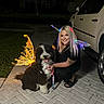 animal, black_and_white_dog, car, costume, cute, dog, driveway, fairy_wings, glowing, happy, kneeling, light, night, outdoor, pavement, person, pet, smiling, suburban, woman