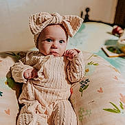 Jaylin is registered to the contest to win money with this photo: baby, infant, child, portrait, clothing, headband, bow, pillow, floral_pattern, cozy, knitwear, cute, indoors, person, face, expression, sitting, soft_lighting, closeup, warm_tones