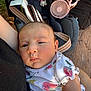 baby, infant, child, person, stroller, clothing, floral_pattern, face, arm, outdoor, fan, accessories, holding, closeup, cute, skin, head, expression, casual, resting