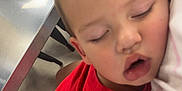 Luis joined the competition — help win amazing prizes! child, toddler, sleeping, red_shirt, shorts, person, table, metal_surface, indoor, casual, resting, face, closed_eyes, short_hair, seated, legs, arm, clothing, people, background