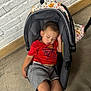 Luis is registered to the contest to win money with this photo: toddler, sleeping, car_seat, red_shirt, spiderman, gray_shorts, indoor, concrete_floor, white_brick_wall, blanket, child, casual_clothing, peaceful, resting, young_child, seat, head_support, casual, person, relaxation