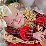 baby, sleeping, infant, bow, headband, lace, red_clothing, plaid, hand, finger, adult_hand, close_up, soft_lighting, cozy, cute, peaceful, portrait, indoors, child, smile