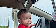 Devon joined the competition — help win amazing prizes! baby, child, car, steering_wheel, red_shirt, tattoo, hand, window, mirror, seat, interior, driving, cute, portrait, infant, expression, grip, young, support, vehicle
