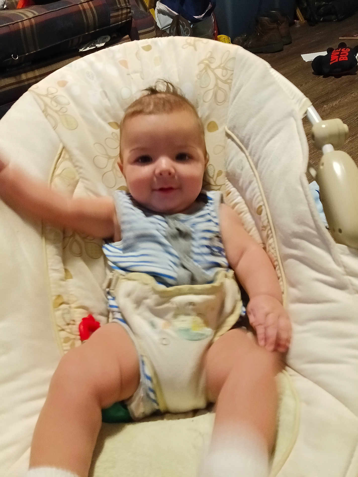 Devon is registered to the contest to win money with this photo: baby, child, infant, baby_rocker, cushion, striped_clothing, smiling, arm_wave, indoor, carpet, sofa, furniture, footwear, floor, toy, home, person, cute, relaxing, young_child