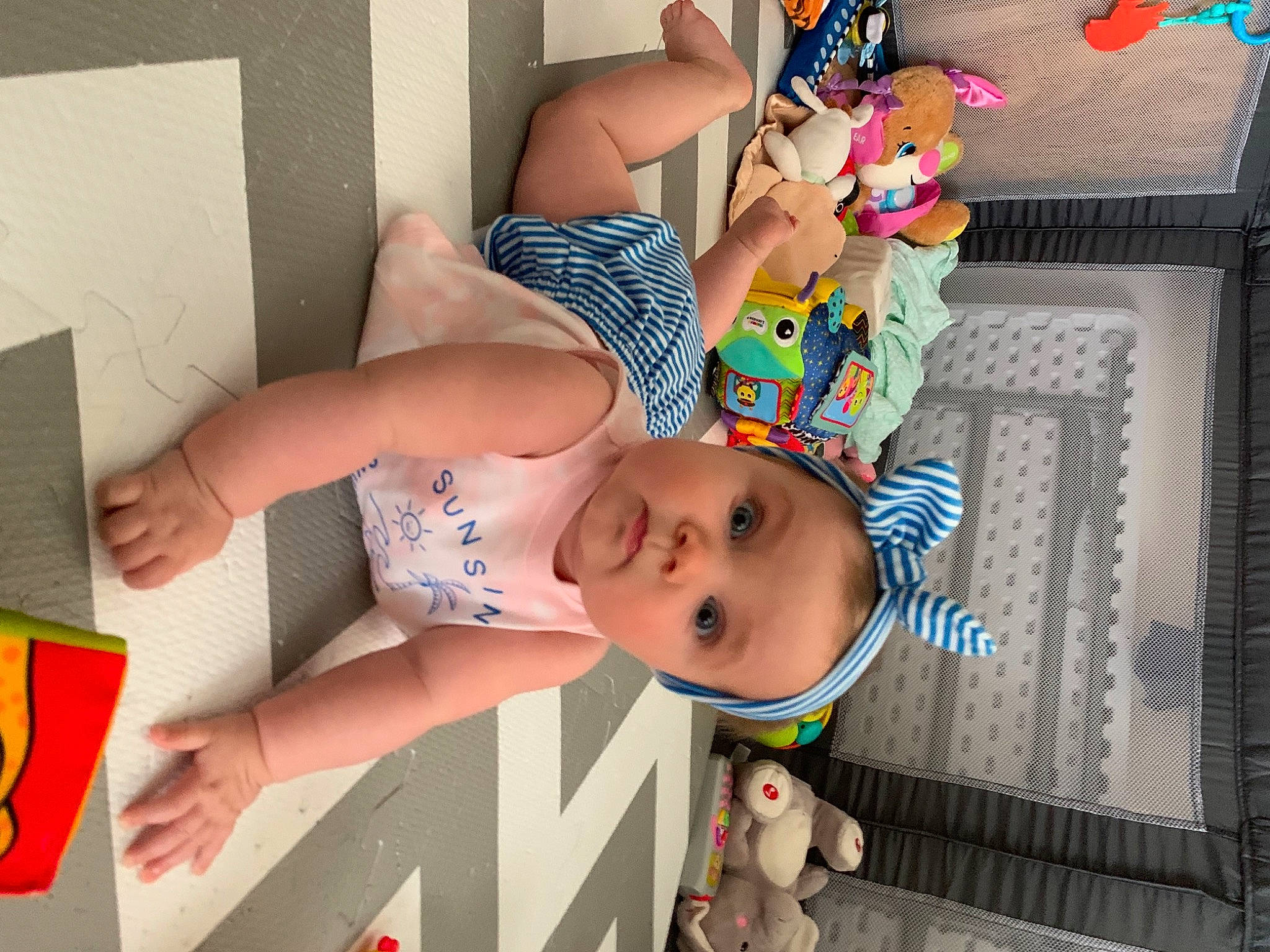 Isabella is registered to the contest to win money with this photo: baby, baby_products, baby_toddler_clothing, chest, child, comfort, flooring, fun, happy, human_leg, pattern, person, play, room, smile, surprise, textile, thigh, toddler, toy