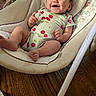 animal_print, baby, baby_bouncer, cheerful, cherries, child, closeup, cushion, family_photo, happy, home, indoor, infant, onesie, playtime, plush_toy, portrait, seated, smiling, wooden_floor