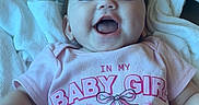 Emma joined the competition — help win amazing prizes! baby, bed, bedroom, blanket, child, cozy, eyes, face, girl, happy, indoor, infant, laughing, lying_down, mouth, onesie, pink_clothing, portrait, smiling, text_on_clothing