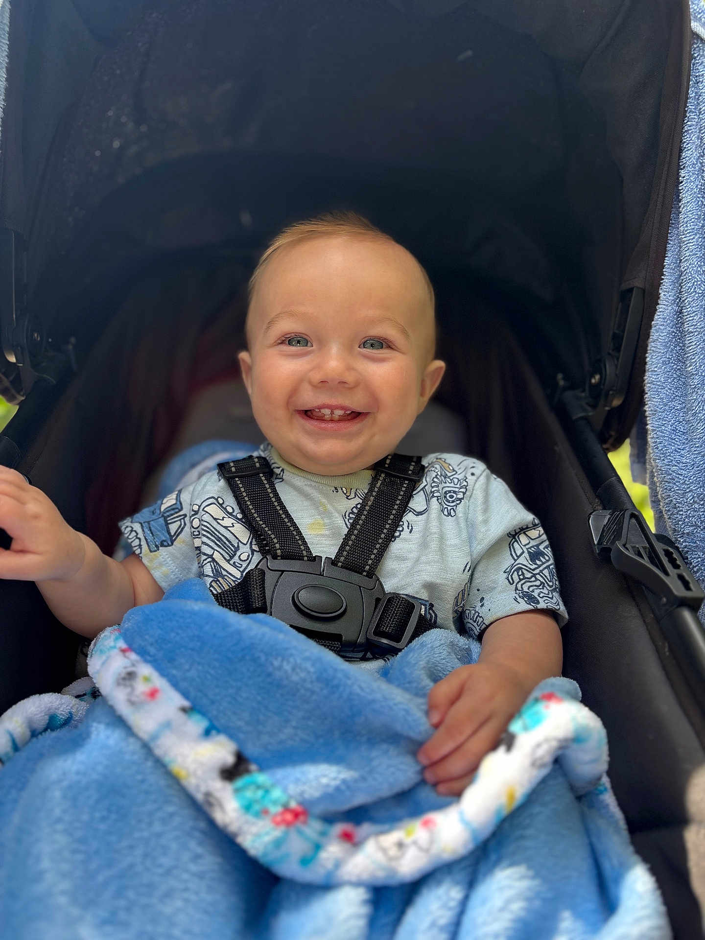 Abel is registered to the contest to win money with this photo: baby, child, smiling, stroller, blanket, blue, happy, infant, face, cute, clothing, sitting, portrait, outside, daylight, person, baby_toy, comfort, cute_expression, baby_harness