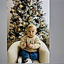 baby, blue_pants, chair, child, christmas_tree, cozy, cute, decorations, festive, holiday, holiday_decor, indoor, lights, ornaments, portrait, seated, sweater, toddler, white_shoes, winter