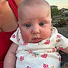 adult, arm, baby, blue_eyes, child, drool, face, floral_pattern, holding, house, infant, nature, onesie, outdoor, person, plants, red_tank_top, skin, sunset, tattoo