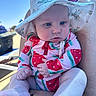 baby, beach, blue_sky, casual, child, closeup, colorful_clothing, daylight, hat, holding, infant, legs, outdoor, person, seated, skin, summer, sun_hat, sunny, watermelon_print