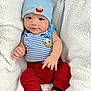 Joab is registered to the contest to win money with this photo: baby, child, infant, hat, blue_hat, teddy_bear, donald_duck, striped_shirt, red_pants, argyle_socks, blanket, cozy, cute, smiling, portrait, indoors, soft_texture, happy, small_hands, seated