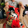 Angel joined the competition — help win amazing prizes! man, dog, blanket, chair, indoor, wooden_floor, casual_clothing, glasses, relaxed, pet, living_room, furniture, resting, looking_at_camera, home, comfort, animal, domestic_dog, person, sitting