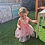 baby, child, curly_hair, daylight, exploring, fence, fun, garden, grass, outdoor, pink_dress, play, shade, summer, sunlight, table, toddler, toy, wicker, young_child