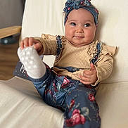 Inaya a rejoint le concours — aidez-le/la à gagner de superbes lots ! baby, child, infant, sitting, chair, headband, smile, cute, playful, foot, sock, floral, clothing, portrait, indoors, furniture, happy, face, person, cozy