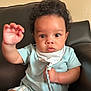 baby, child, curly_hair, light_blue_shirt, pacifier_clip, sitting, leather_chair, indoors, cute, portrait, young_child, face, hand, expression, eyes, clothing, furniture, background, skin, infant