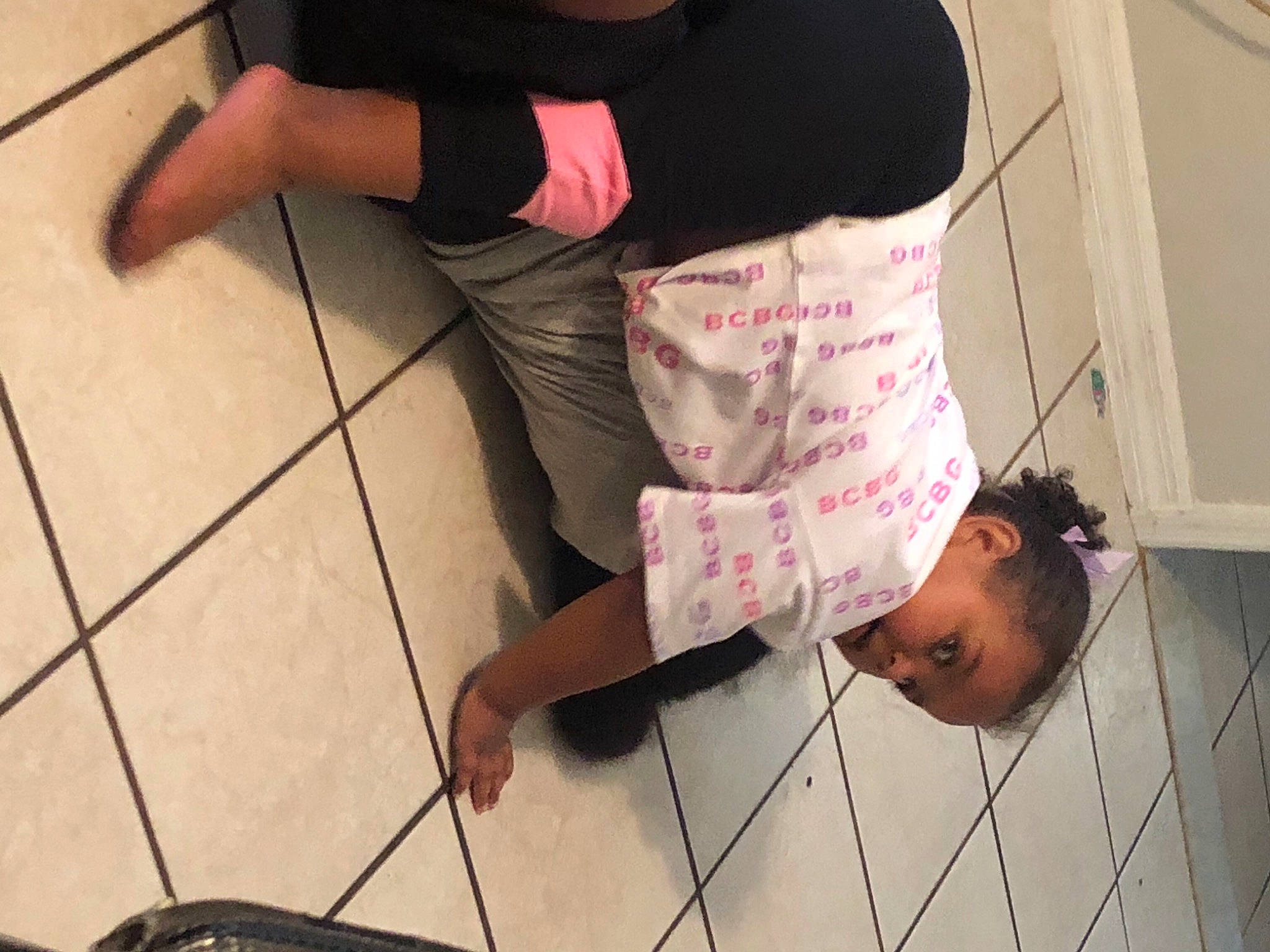 Khalia is registered to the contest to win money with this photo: arm, black, child, elbow, floor, flooring, foot, hand, hardwood, human_leg, joint, knee, leg, pattern, person, sitting, sleeve, thigh, waist, wood