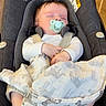 baby, baby_clothing, blanket, car_seat, child, comfort, door, floor, footwear, furniture, home, indoor, infant, pacifier, person, rest, seat_belt, sleeping, socks, zebra_print
