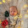 baby, infant, onesie, animal_print, mittens, fluffy_rug, fairy_lights, glowing_lights, gift_bows, red_bow, green_bow, gold_bow, smile, face, cute, holiday_theme, cozy, indoor, portrait, soft_texture