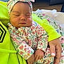 baby, sleeping, infant, floral_pattern, headband, hand, hoodie, neon_green, onesie, person, blanket, cozy, cute, peaceful, indoor, closeup, soft_lighting, portrait, child, resting