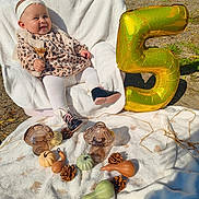 Ruby a rejoint le concours — aidez-le/la à gagner de superbes lots ! baby, child, balloon, number_five, blanket, outdoor, autumn, pinecone, pumpkin, glass_decor, white_tights, leopard_print, headband, smiling, sitting, sunlight, grass, cozy, decorations, shoes
