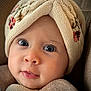 baby, face, hat, knitted_hat, blue_eyes, close_up, portrait, child, cute, expression, floral_embroidery, warm_clothing, soft_lighting, infant, apparel, headwear, skin, eyelashes, cozy, neutral_colors