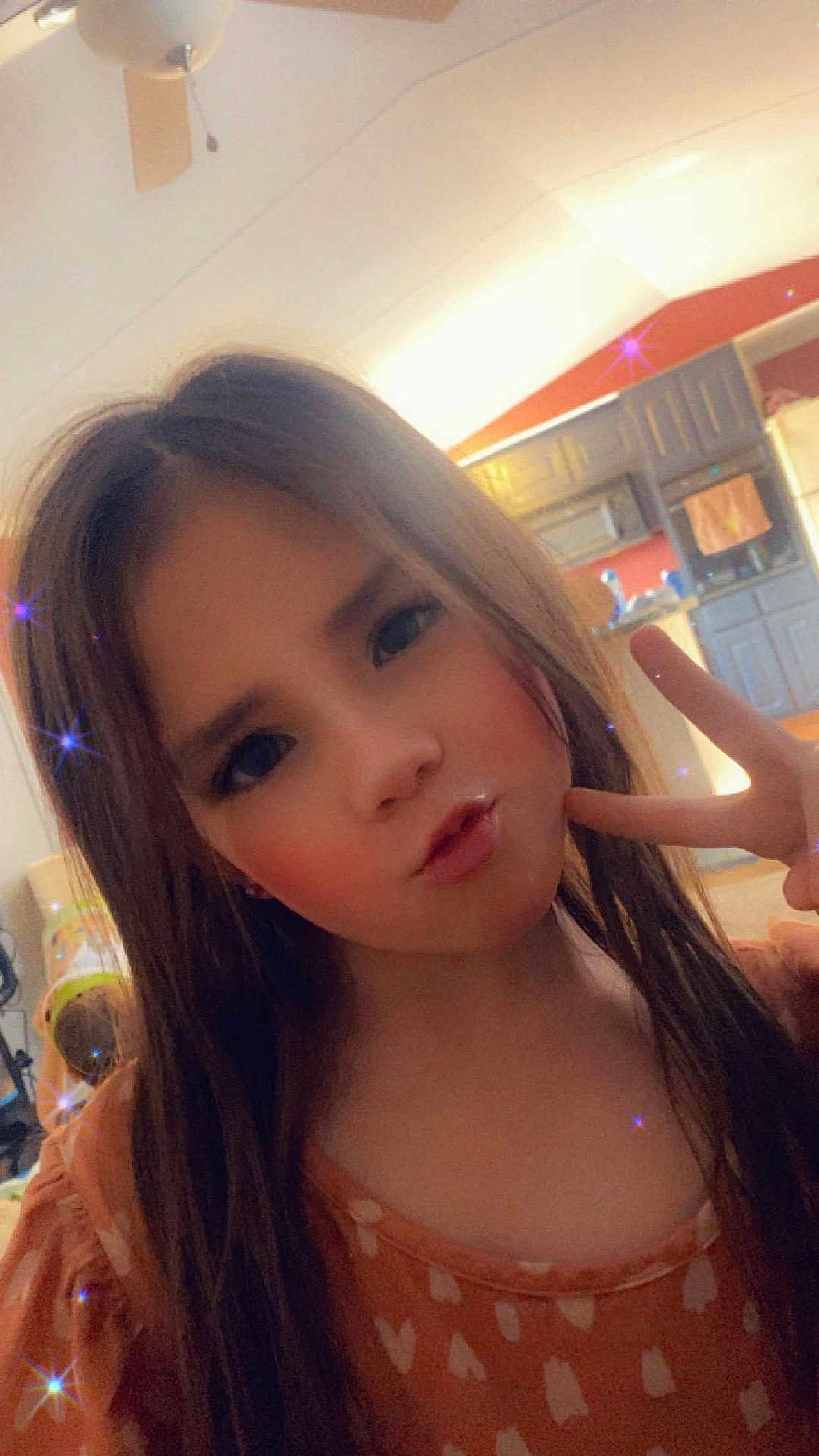 Kylie joined the competition — help win amazing prizes! child, girl, peace_sign, posing, long_hair, orange_dress, sparkle_filter, indoor, kitchen, cabinet, ceiling_fan, lighting, playful, pout, portrait, young, smiling_eyes, casual, home, person