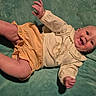 baby, infant, smiling, clothing, yellow_shorts, cream_top, deer_print, blanket, green_blanket, happy, cute, hands, legs, face, portrait, lying_down, child, indoors, soft_texture, toddler