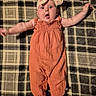 Journee is registered to the contest to win money with this photo: baby, child, infant, plaid_blanket, orange_outfit, headband, bow, wide_eyes, surprised_expression, arms_outstretched, barefoot, lying_down, fabric_texture, indoor, person, cute, small, soft_lighting, portrait, young