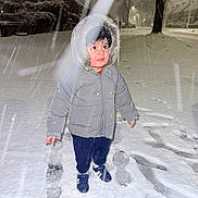 Muhammad Ibrahim joined the competition — help win amazing prizes! child, toddler, snow, winter, coat, hood, footprints, night, streetlight, snowfall, outdoor, cold, jacket, pants, shoes, curious, standing, urban, trees, sidewalk