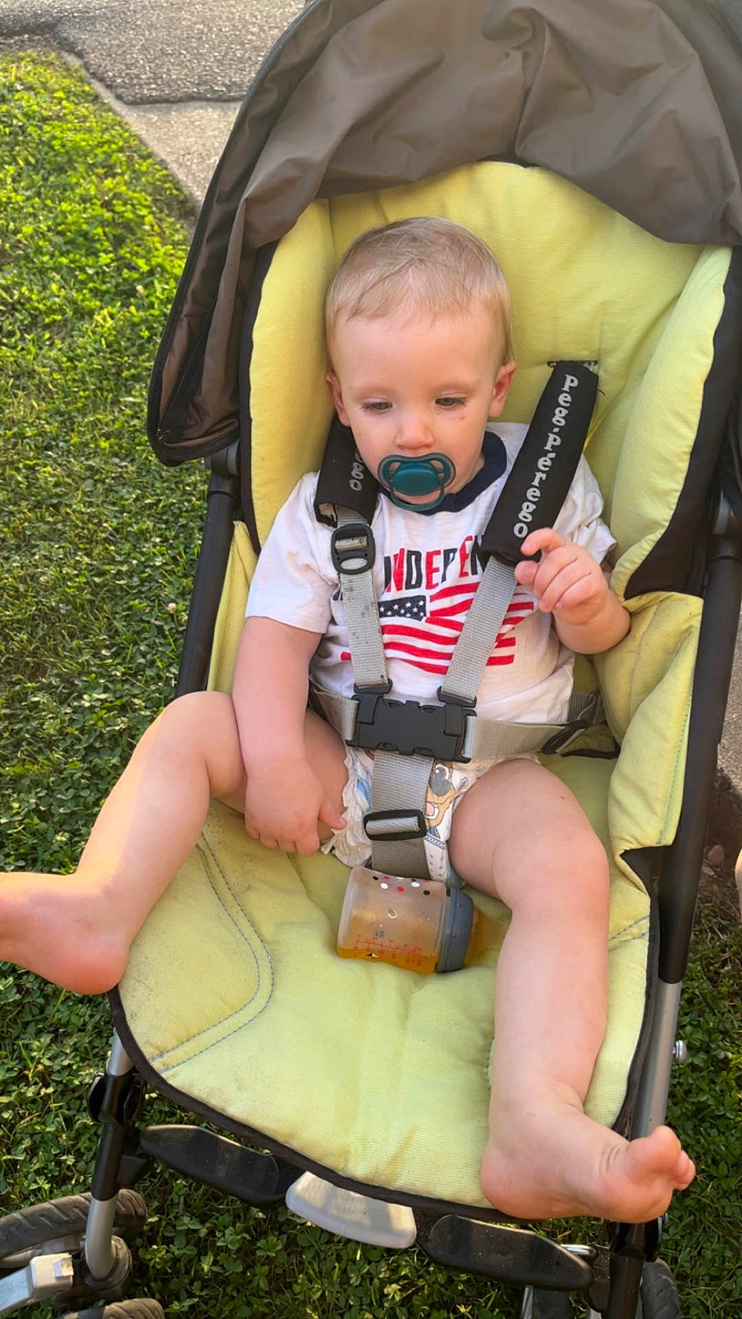 Malachi joined the competition — help win amazing prizes! toddler, child, stroller, pacifier, bottle, grass, sidewalk, outdoor, clothing, baby, seatbelt, yellow_cushion, foot, hand, person, casual, daylight, relaxed, infant, summer