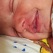 Darlene is registered to the contest to win money with this photo: baby, sleeping, closeup, face, skin, mouth, nose, eyelashes, fabric, pattern, animal_print, cute, resting, peaceful, infant, child, soft, comfort, portrait, young