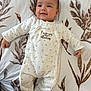 Léo a rejoint le concours — aidez-le/la à gagner de superbes lots ! baby, infant, smiling, onesie, clothing, bedspread, pattern, floral, laying_down, cute, face, skin, hand, footed_pajamas, sleepwear, child, indoors, young, expression, comfort