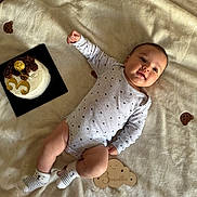 Léo participe au concours pour gagner de l'argent avec cette photo : baby, infant, blanket, cake, celebration, milestone, onesie, socks, face, lying_down, cute, teddy_bear_pattern, wooden_plaque, 3_months, smile, happy, soft_texture, indoor, portrait, child
