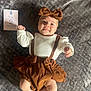 baby, infant, smiling, headband, bow, brown_clothing, white_shirt, milestone_card, blanket, texture, lying_down, cute, happy, two_months, skin, foot, hand, portrait, indoors, child