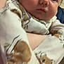 Easton is registered to the contest to win money with this photo: baby, infant, onesie, animal_print, close_up, face, person, cute, child, hand, arm, clothing, indoor, portrait, soft, warm, young, expression, holding, skin