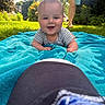 baby, towel, grass, outdoor, smile, person, barefoot, sunlight, blue, happy, infant, face, child, nature, daylight, casual, greenery, playful, summer, relaxation