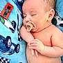 baby, infant, sleeping, pacifier, toy_car, blue_blanket, patterned_blanket, newborn, bare_torso, hand, face, ear, closed_eyes, chubby_cheeks, peaceful, cozy, soft_texture, portrait, infant_sleep, plaything