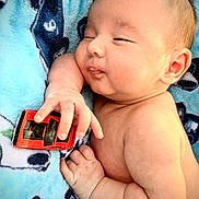 Zander joined the competition — help win amazing prizes! baby, blanket, blue, child, closeup, cute, expression, face, hand, human, infant, lying_down, newborn, playful, relaxed, skin, sleepy, small_toy, soft_texture, toy_car
