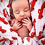 baby, newborn, infant, swaddle, blanket, red_car_pattern, sleeping, peaceful, cute, hand, fingers, face, portrait, closeup, soft_texture, skin, eyelashes, cozy, newborn_photography, nursery
