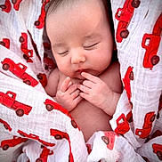 Zander joined the competition — help win amazing prizes! baby, newborn, infant, sleeping, swaddled, blanket, red_truck, car_print, pattern, cute, sleepy, portrait, hands, fingers, skin, soft_texture, nursery, closeup, peaceful, adorable