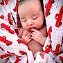 baby, newborn, infant, sleeping, swaddled, blanket, red_truck, car_print, pattern, cute, sleepy, portrait, hands, fingers, skin, soft_texture, nursery, closeup, peaceful, adorable