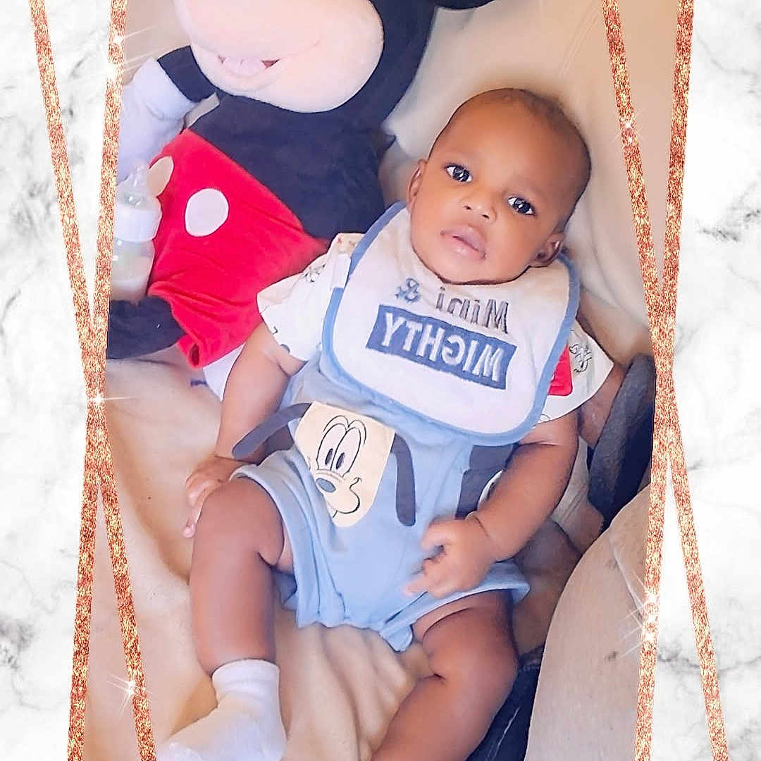 Cameron joined the competition — help win amazing prizes! baby, child, mickey_mouse, plush_toy, bib, couch, marble_background, sparkle_border, sitting, clothing, smiling, cute, indoor, portrait, person, toy, infant, comfortable, decorative_frame, young_child