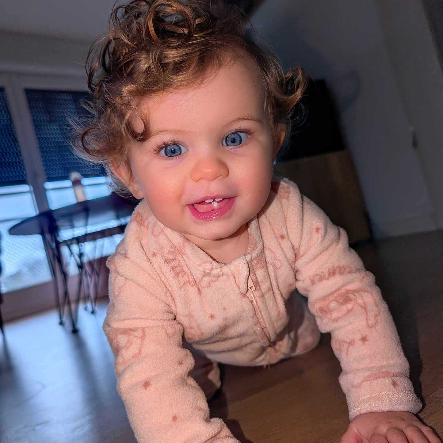 Lily-Rose a rejoint le concours — aidez-le/la à gagner de superbes lots ! baby, blue_eyes, chair, child, closeup, crawling, curly_hair, face, floor, furniture, hands, happy, home, indoor, natural_light, onesie, person, smiling, table, wooden_floor