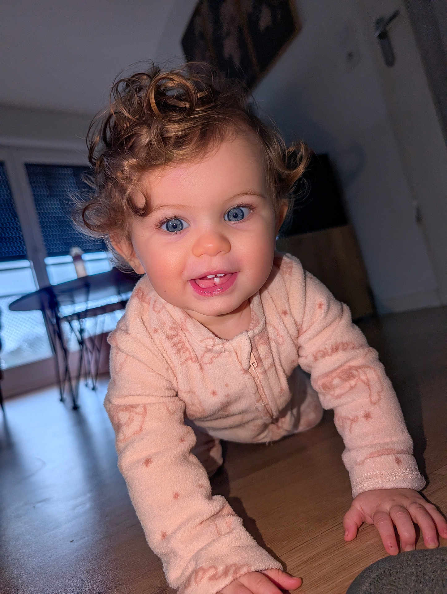Lily-Rose a rejoint le concours — aidez-le/la à gagner de superbes lots ! baby, blue_eyes, chair, child, closeup, crawling, curly_hair, face, floor, furniture, hands, happy, home, indoor, natural_light, onesie, person, smiling, table, wooden_floor
