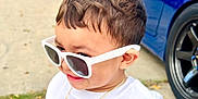 Liam joined the competition — help win amazing prizes! toddler, child, sunglasses, white_shirt, gold_chain, gold_ring, outdoor, driveway, car, blue_car, house, sidewalk, person, smiling, fashion, jewelry, cool, cute, young_child, casual