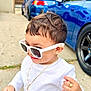 toddler, child, sunglasses, white_shirt, gold_chain, gold_ring, outdoor, driveway, car, blue_car, house, sidewalk, person, smiling, fashion, jewelry, cool, cute, young_child, casual