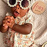 Naioir joined the competition — help win amazing prizes! baby, infant, flower_sunglasses, floral_dress, blanket, wooden_sign, four_months, cute, smiling, lying_down, headband, skin, hands, portrait, child, young, indoors, cozy, celebration, milestone