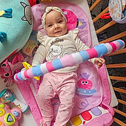 Selma participe au concours pour gagner de l'argent avec cette photo : baby, child, colorful, crib, cute, happy, headband, indoors, infant, lying_down, maraca, piano_toy, pink_clothing, playmat, playtime, smiling, soft_toy, stuffed_animal, toy, wooden_bars